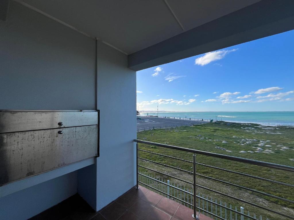 a room with a balcony with a view of the beach at Boardwalk 11 in Struisbaai