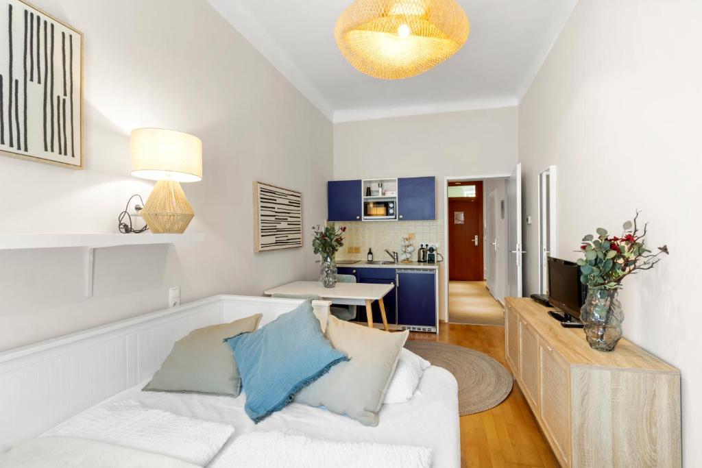 a living room with a white couch and a kitchen at Bright City Hideaway, Augarten and Danube - 5 min Metro - 10 min Center in Vienna