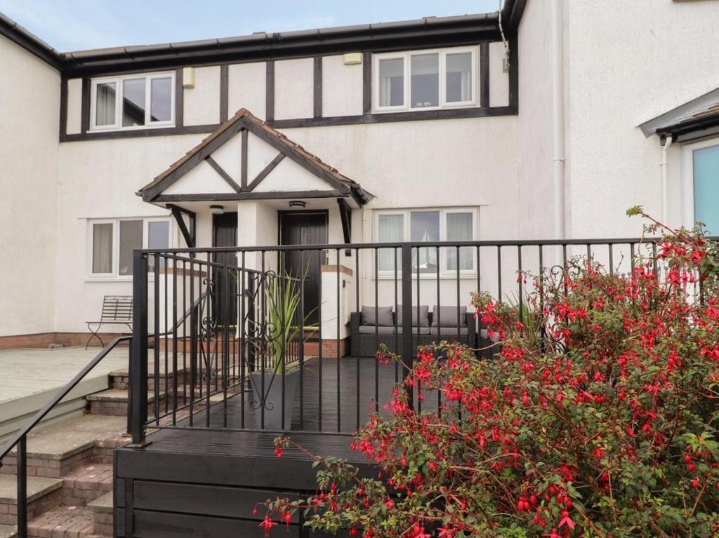a house with a black fence and red flowers at Castle View in Deganwy