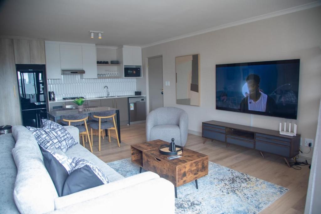 a living room with a couch and a tv at Beachside Modern Holiday Apartments in Cape Town