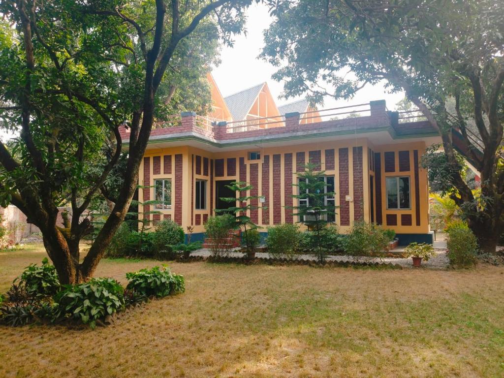 a large house with a tree in front of it at Corbett Bungalow Stay- Private Garden Stay Near Jim Corbett in Rāmnagar