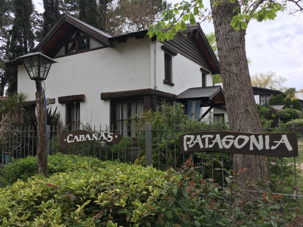 una casa blanca con un letrero de la calle delante de ella en Cabañas Patagonia en Villa Gesell