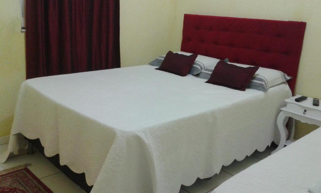 Schlafzimmer mit einem großen weißen Bett mit einem roten Kopfteil in der Unterkunft Pousada Villas Colossos in Lençóis