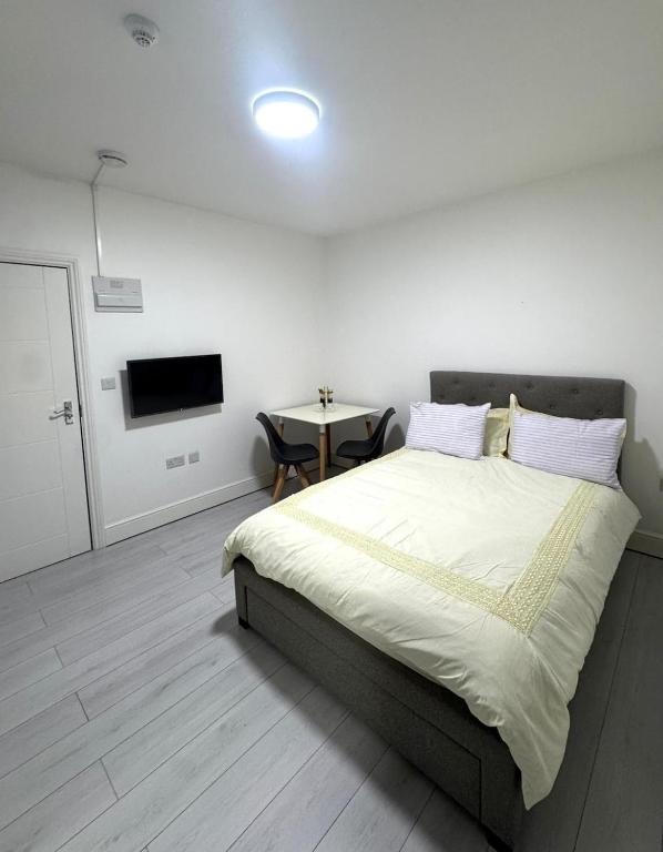a bedroom with a large bed and a table at Cozy Golders Green Studio Flat in Moffat