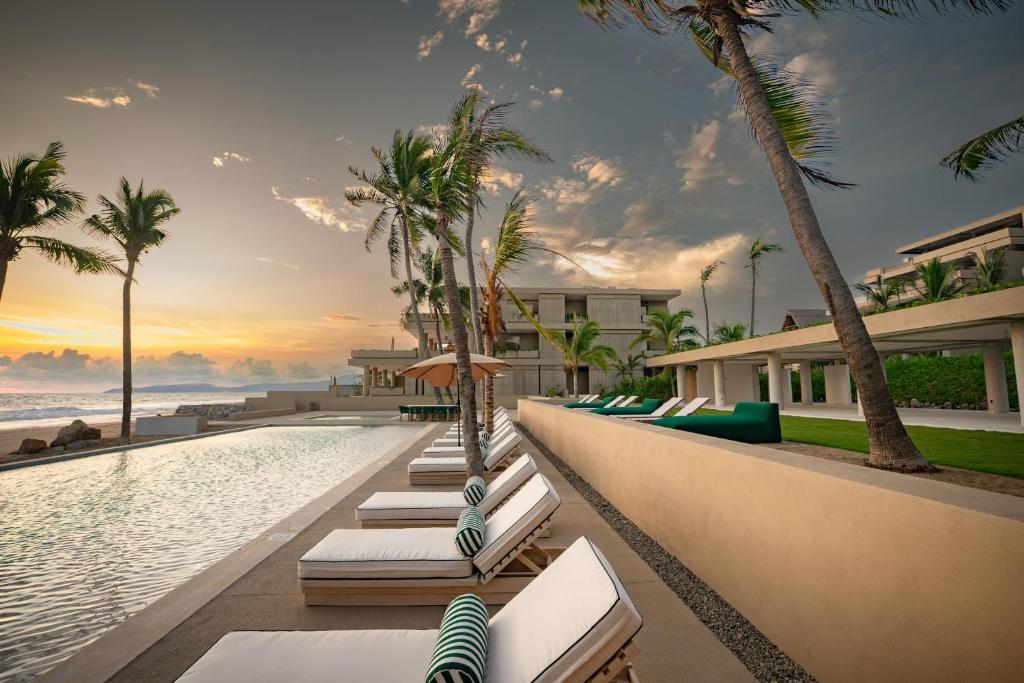 a resort swimming pool with lounge chairs and palm trees at Anera Villas in Barra de Potosi