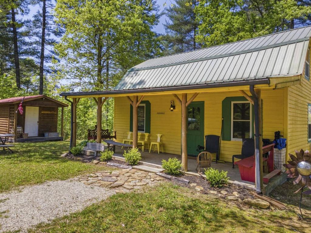a yellow house with a porch and a patio at Knotty By Nature- Pet Friendly, Firepit, 150 Acres in Campton