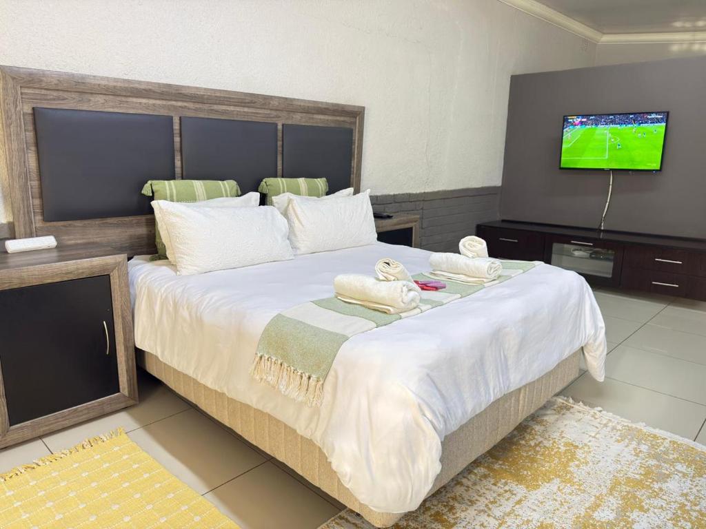 a bedroom with a large bed with towels on it at Palm Guesthouse in Zeerust