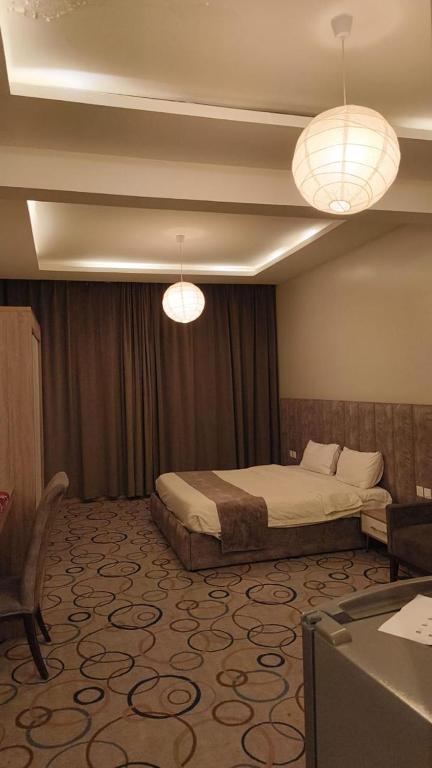 a bedroom with a bed and two chandeliers at شقق أبهى المضياف الذهبية للشقق المخدومة in Abha