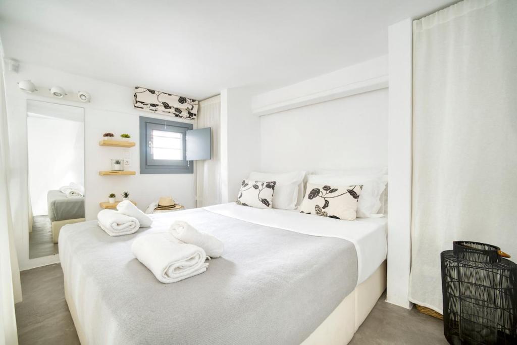 a white bedroom with two beds with towels on them at Mykonos Yialos Town Home Loft - by Hospirit in Mikonos