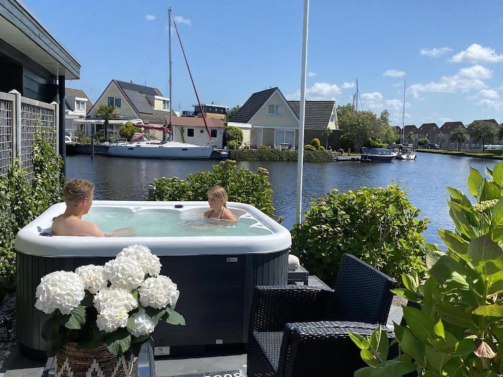a man and a woman in a hot tub next to a river at Aquaronde 122 in Lemmer