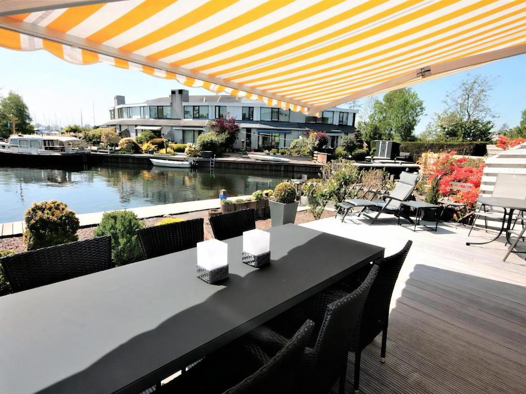 a table and chairs on a patio with a view of a river at Park Brekkense Wiel 058 in Lemmer