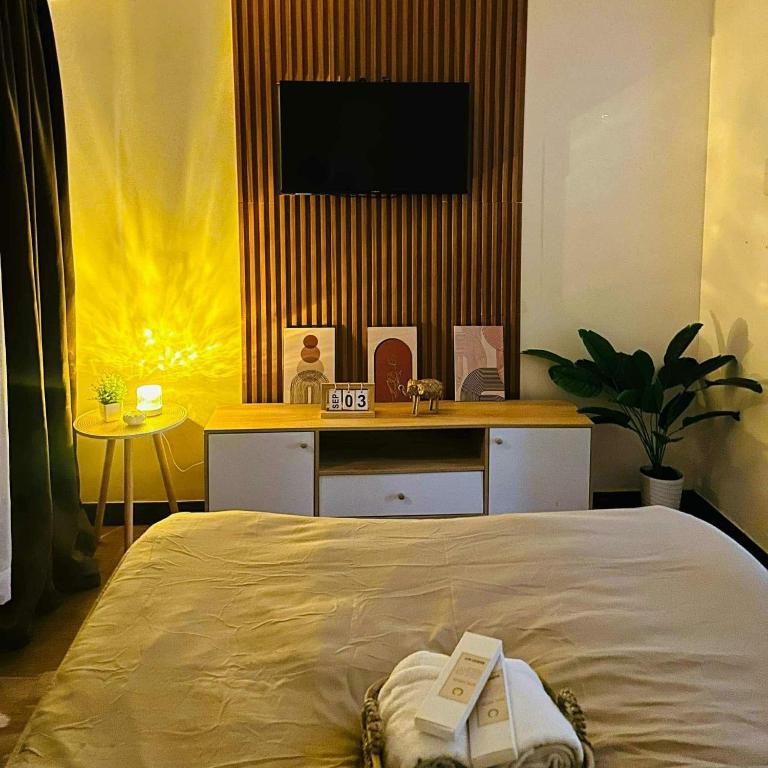 a bedroom with a bed and a tv on a wall at Celeste Stays- Celandine in Sampong