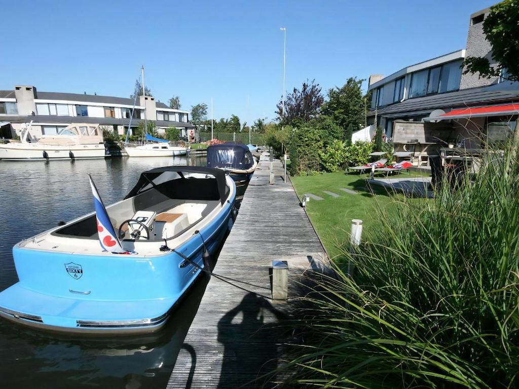 a blue boat docked at a dock in the water at Park Brekkense Wiel 069 in Lemmer