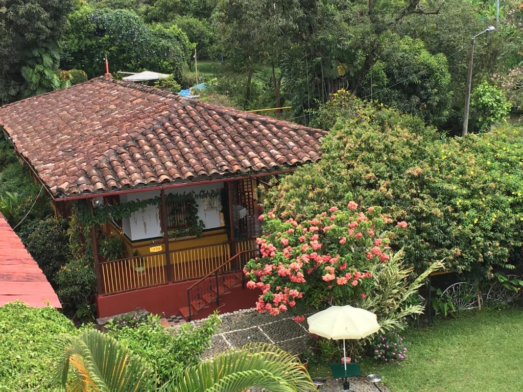 a small house in a garden with flowers and an umbrella at Finca Machangara in Quimbaya