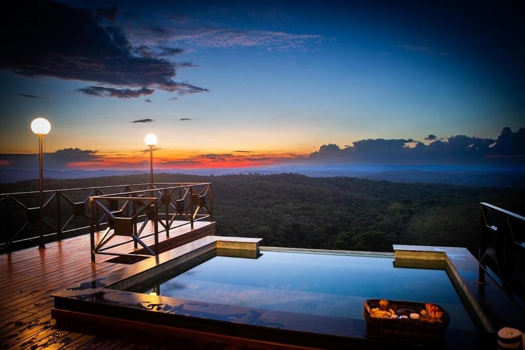 a pool on a deck with a sunset in the background at Cipó Cabanas in Santana do Riacho