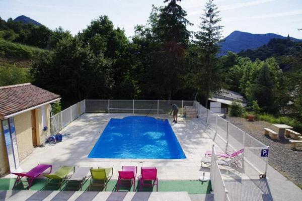 a swimming pool with chairs and a man standing next to it at Camping L'Amandier in Gigors