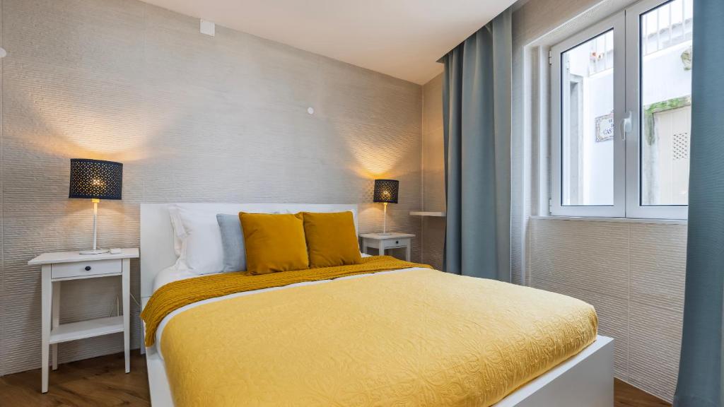 a bedroom with a bed with yellow sheets and a window at Sítio do Castelo Beach in Cascais by LovelyStay in Cascais