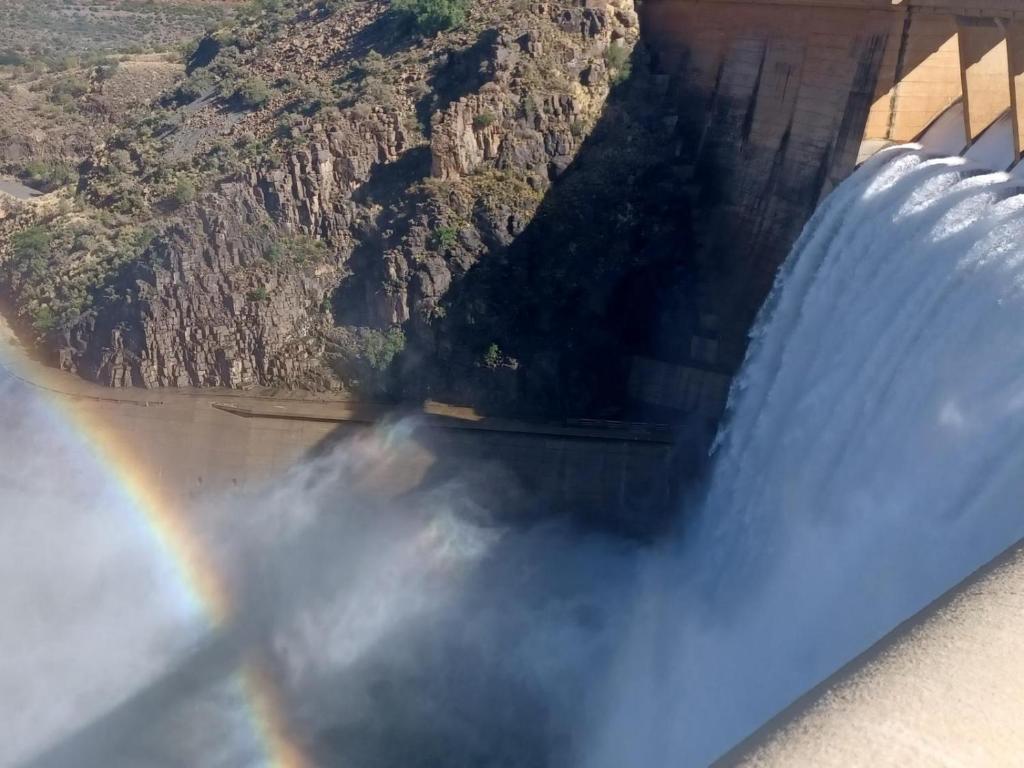 a rainbow over a dam with a mountain in the background at OppiDam Gastehuis in Vanderkloof