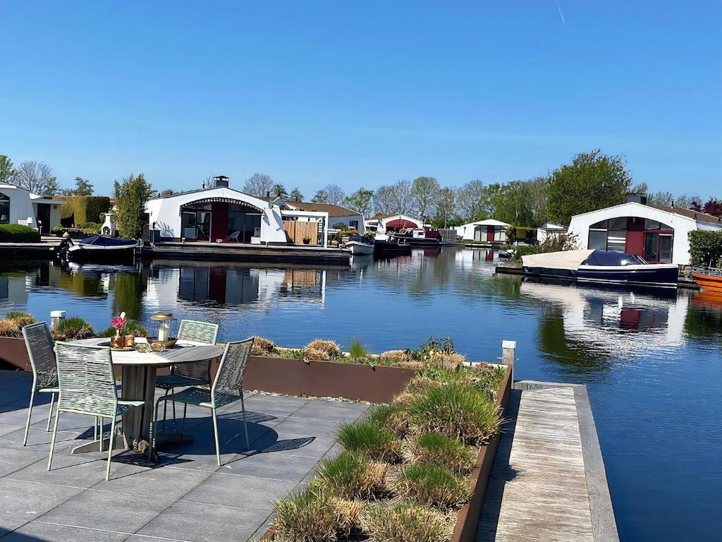 a table and chairs next to a river with boats at Aquaronde 073 in Lemmer