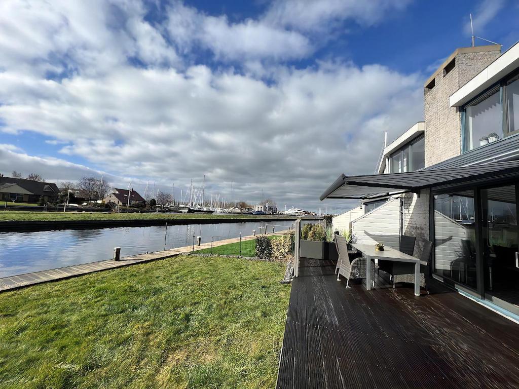 a house with a table and benches next to a river at Park Brekkense Wiel 037 in Lemmer