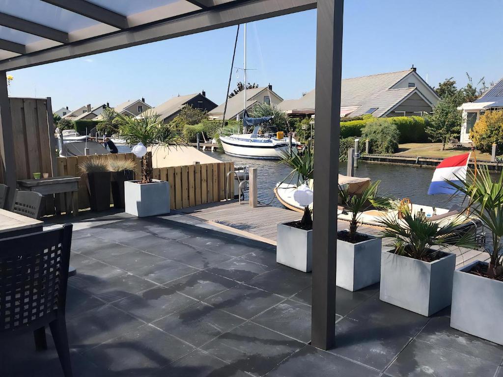a patio with potted plants and a boat in a marina at Park De Markol River House in Lemmer