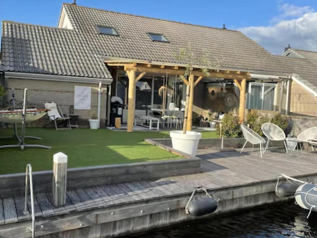 a house with a deck with chairs on the water at Park De Markol Love Lemmer in Lemmer