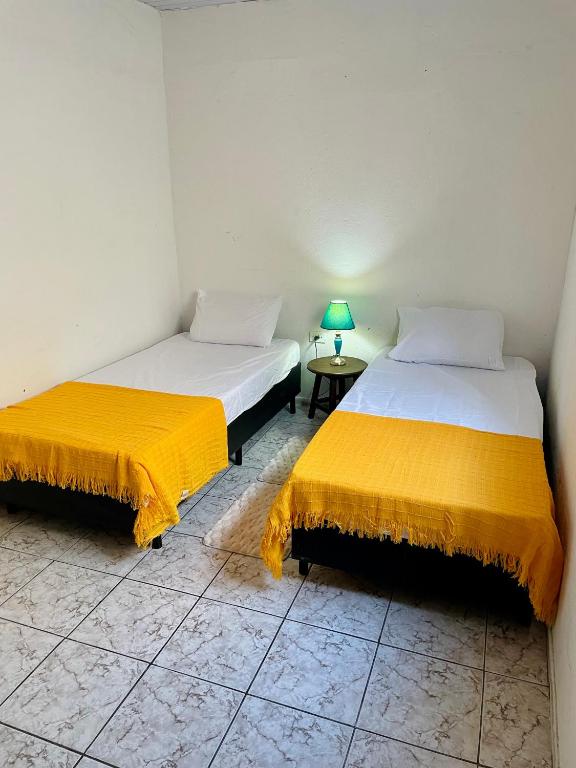 a room with two beds and a table with a lamp at Cantinho do Sol in Recife