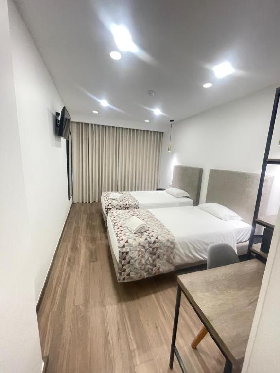 a room with two beds and a table in it at Hotel Flamingo in Lisbon