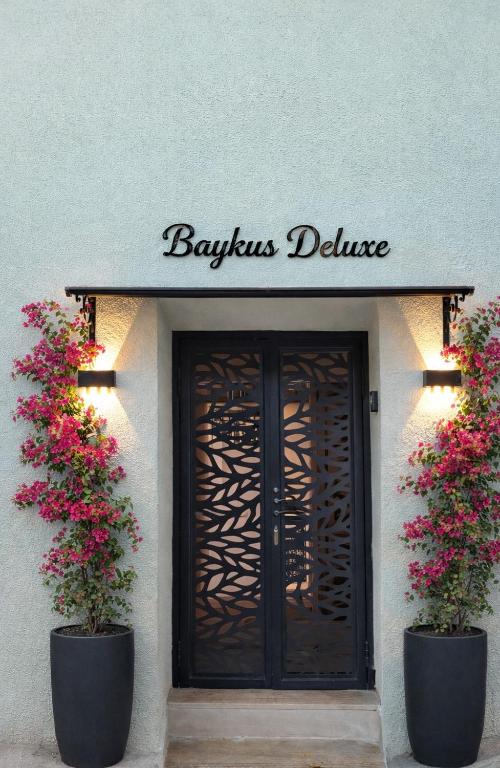a building with a sign above a door with flowers at Baykus Deluxe in Kuşadası