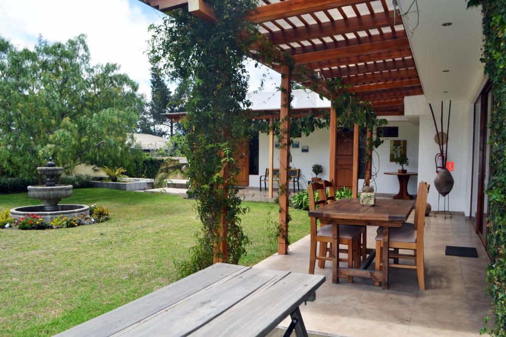 eine Terrasse mit einem Holztisch und einer hölzernen Pergola in der Unterkunft Casa del Viajero in Pifo