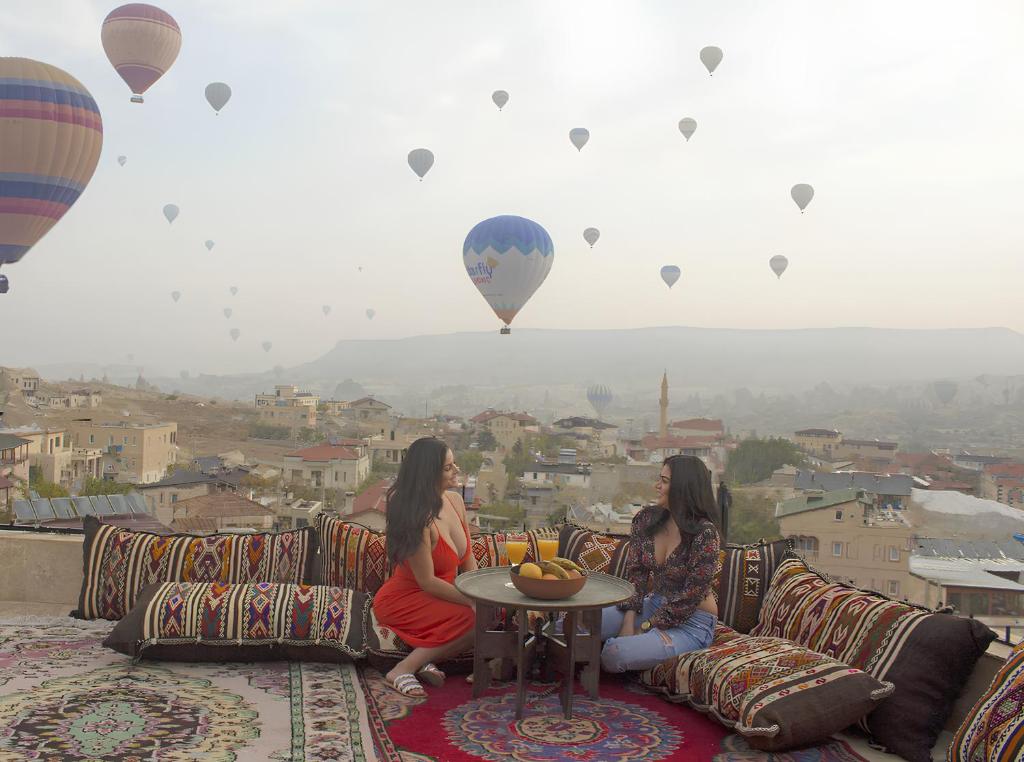 two women sitting on a couch watching hot air balloons at Kismet Cave Mansion in Göreme
