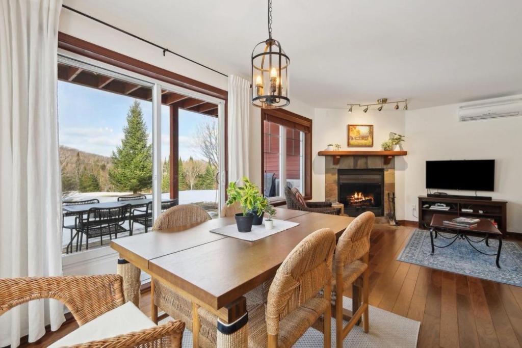 a dining room with a table and a fireplace at Cozy Golfside Oasis Fireplace and Terrace in Mont-Tremblant