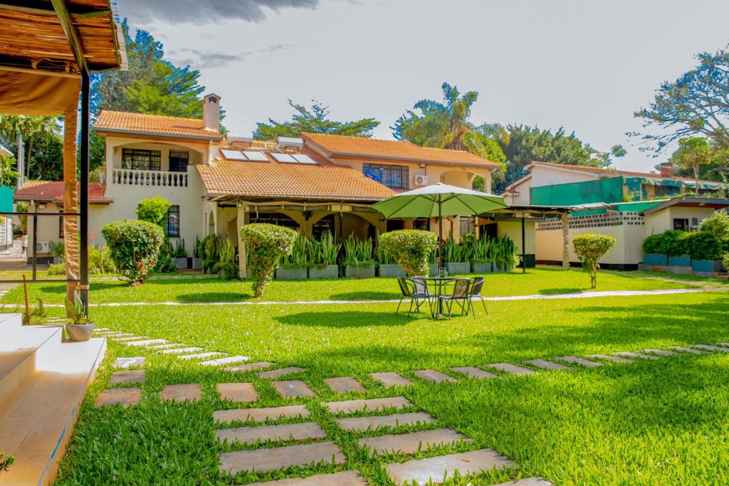 a yard with a table and a house at Cozy Stead Hotel - Garden House, Gigiri in Nairobi
