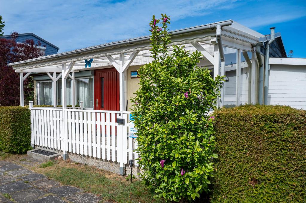 a white house with a red door and a bush at Turmhaus Mönkebude in Mönkebude