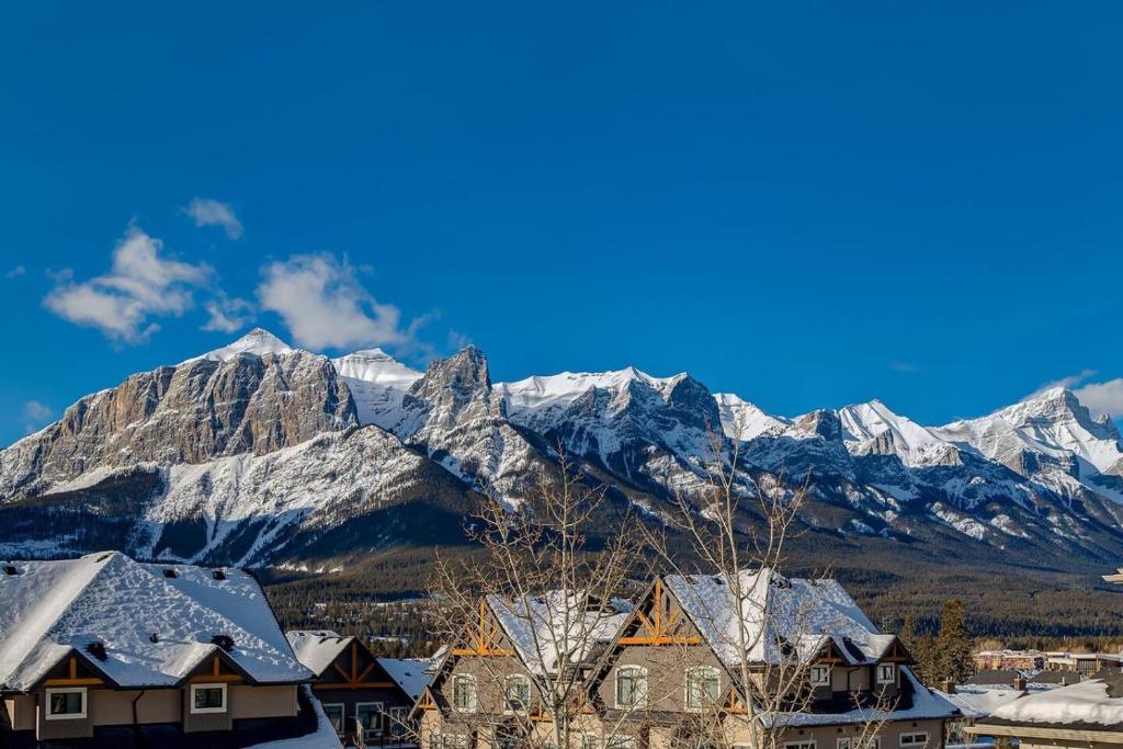a village with snow covered mountains in the background at Stylish Mountain View Condo with Gym in Canmore