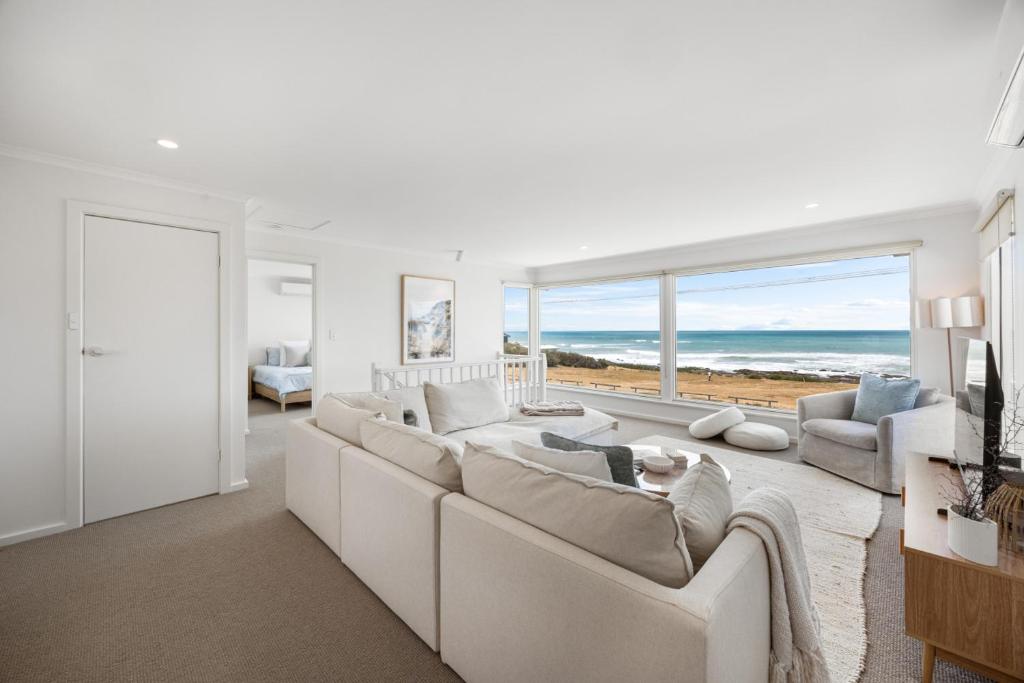 a living room with a white couch and a view of the ocean at Nest at Bashams - A Panoramic Oceanfront Sanctuary in Middleton