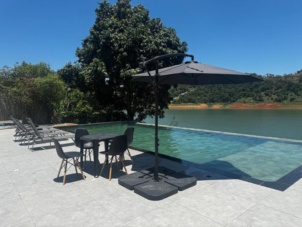 a table and chairs with an umbrella next to a pool at Resilience Igaratá in Igaratá