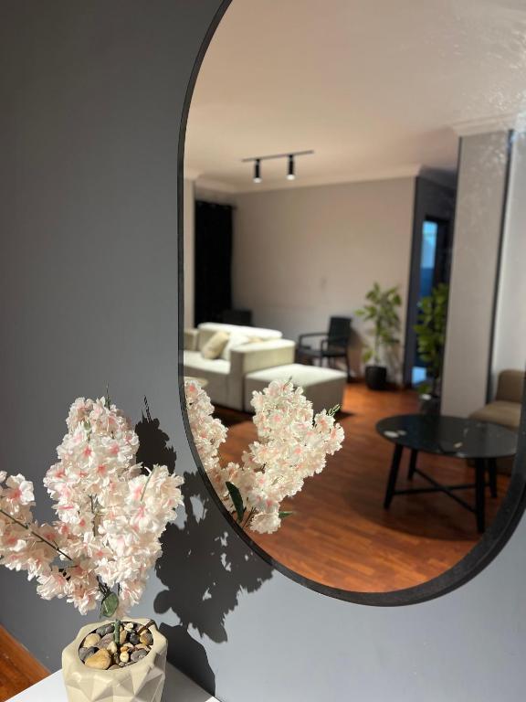 a mirror on a wall with flowers in a living room at Tara Home 44 in Sheikh Zayed