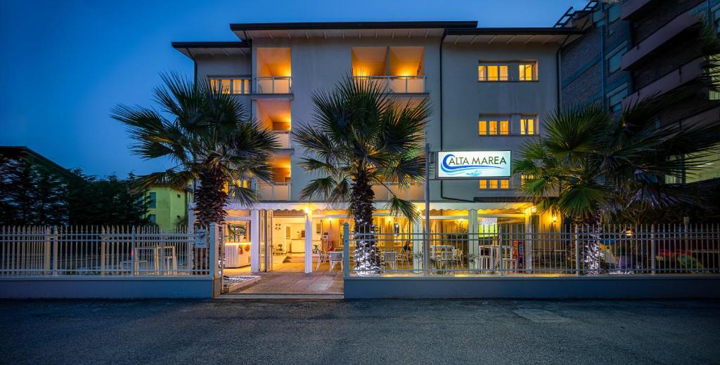 a building with palm trees in front of it at Hotel Altamarea Cesenatico in Cesenatico