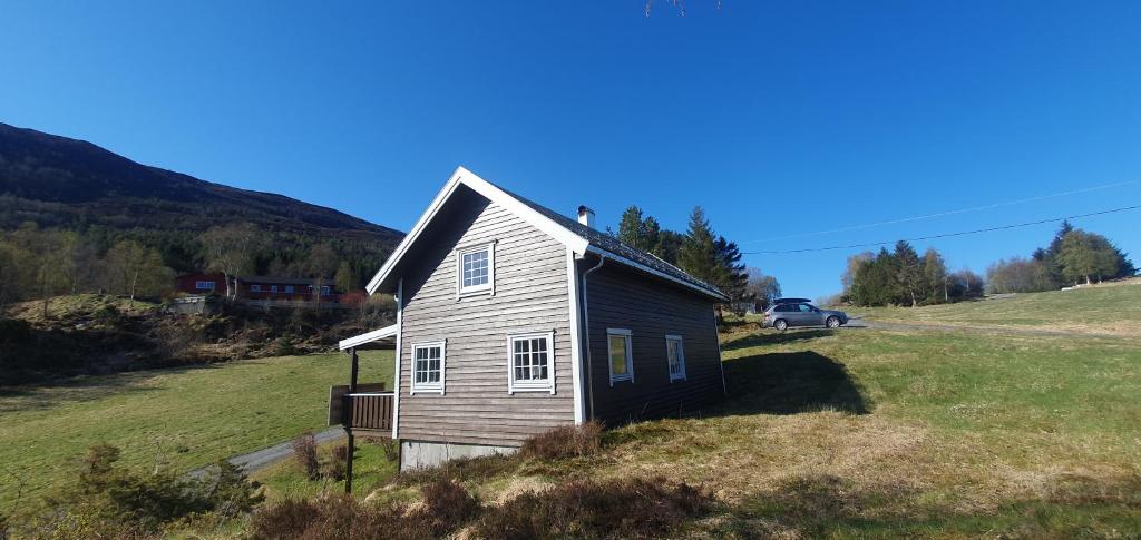 a small house in a field with a car parked at Sunset Cabin in Ålesund