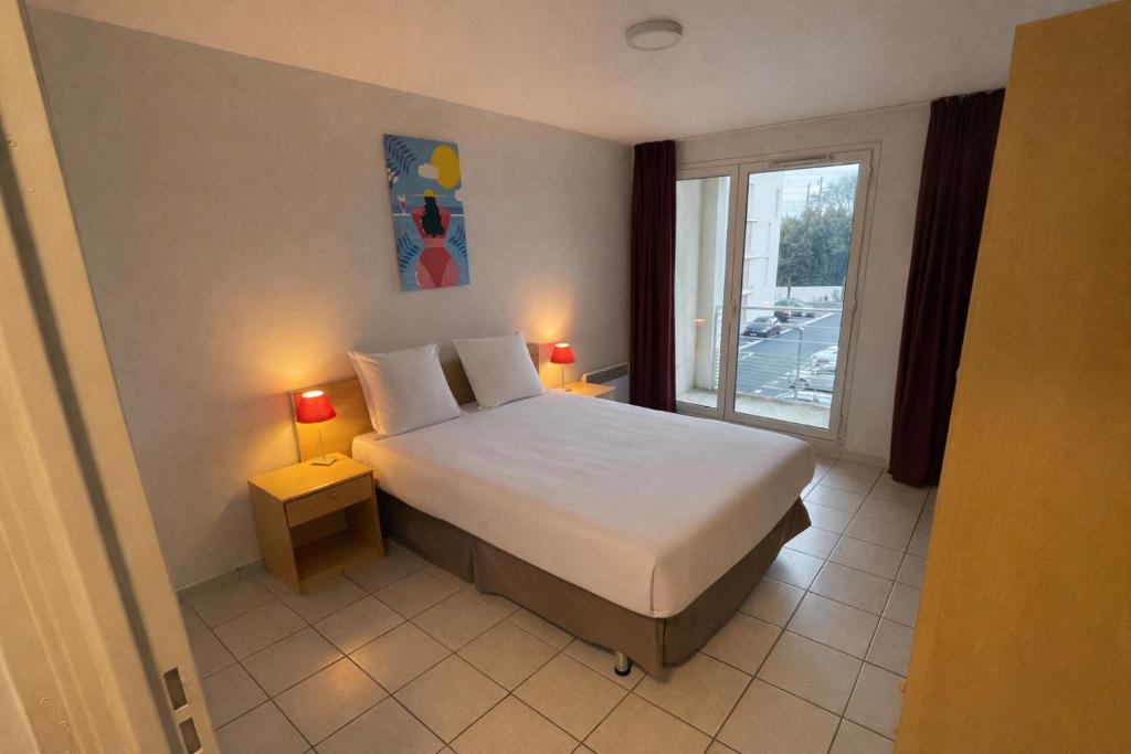 a bedroom with a large bed and a window at City Résidence Avignon in Avignon