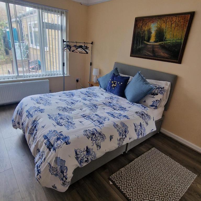 a bedroom with a bed with a blue and white comforter at Clover Crest - 3-Bedroom House in Bourton on the Water