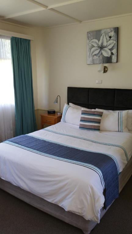 a bedroom with a large bed with a blue and white blanket at Kaniva Midway Motel in Kaniva