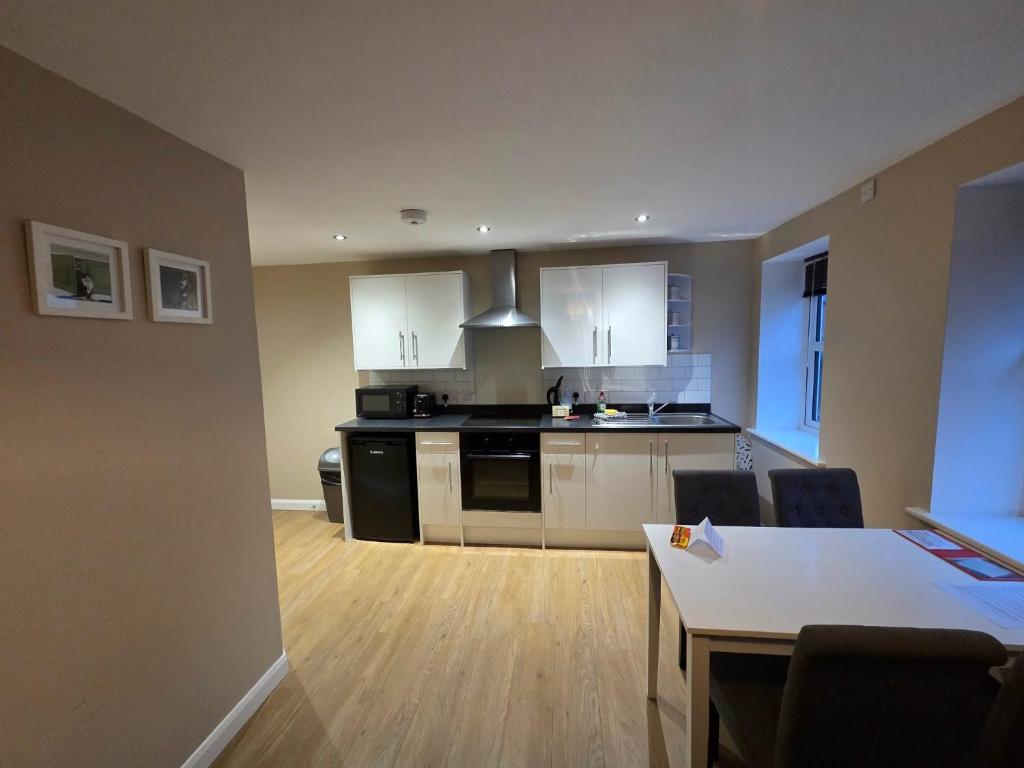 a kitchen with white cabinets and a table with chairs at 4b Smart Apartments in Newark-on-Trent