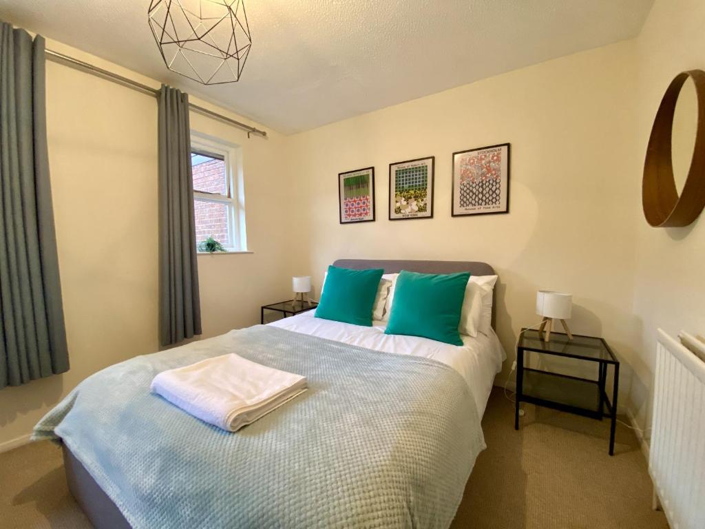 a bedroom with a bed with blue and green pillows at Comfortable 2 Bedroom House in Bracknell in Bracknell