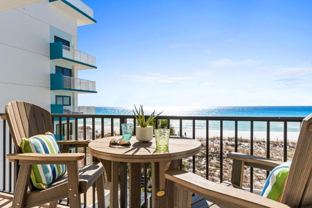 a balcony with a table and chairs and the ocean at Dune Pointe 402 - Shells, Surf & Sea Turtles in Fort Walton Beach