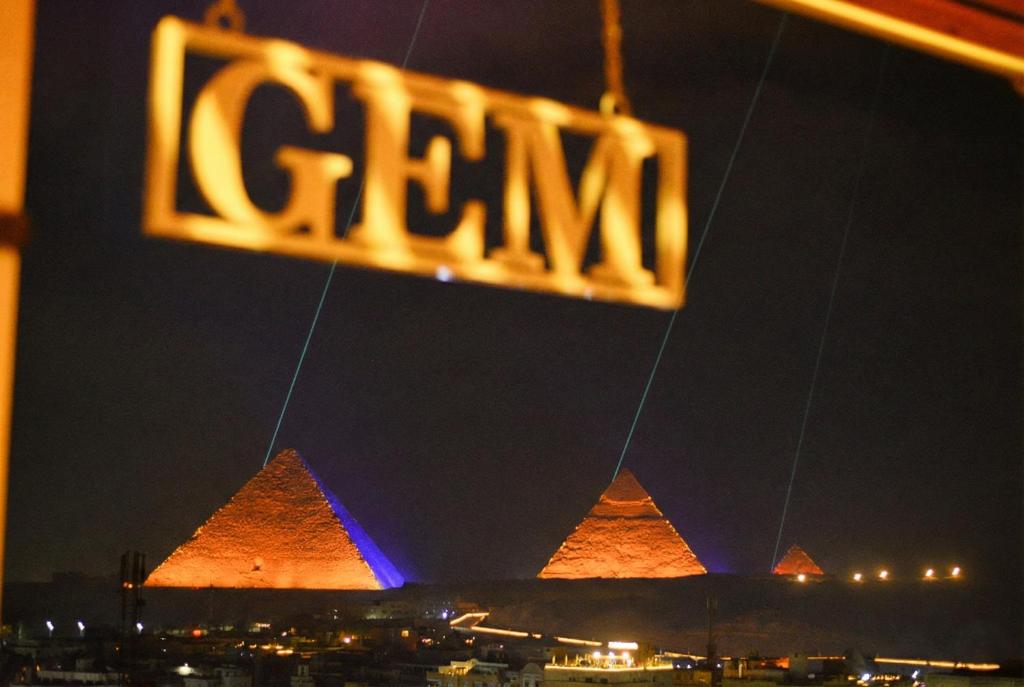 a sign in front of the pyramids at night at GEM Pyramids & Grand Museum View in Cairo