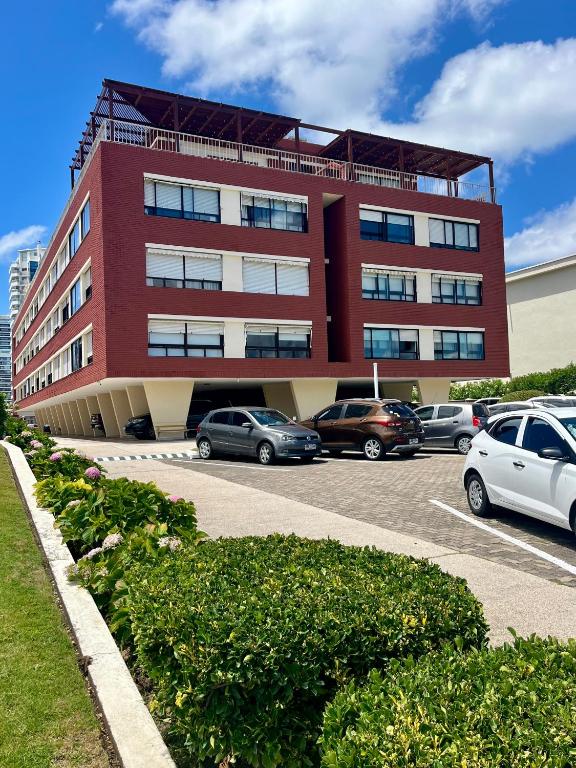a red building with cars parked in a parking lot at Edificio Carbe Punta del Este - Frente al Mar -parada 2 de la Mansa in Punta del Este