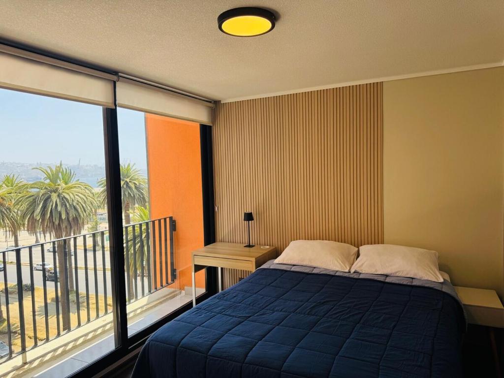 a bedroom with a blue bed and a balcony at Studio Frente Al Muelle Barón in Valparaíso