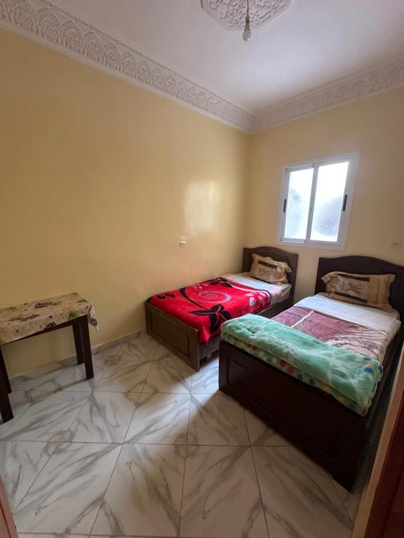 a bedroom with two beds and a window at Apparemment tafoukt in Tafraout